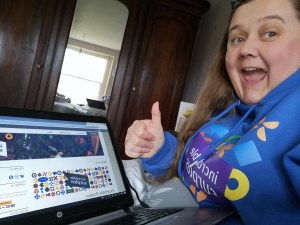 Volunteer using a laptop to look at the Incredible Surplus Website and giving it a thumbs up.